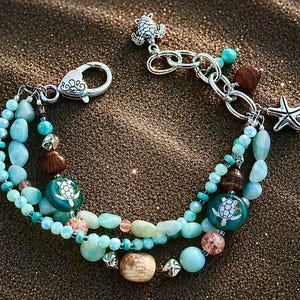 May include: A layered bracelet with turquoise and brown beads, accented with a starfish charm and a turtle charm. The bracelet features a mix of round and irregular-shaped beads, creating a beachy aesthetic.