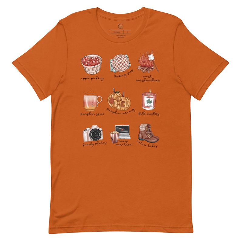 May include: Orange t-shirt with a white graphic of fall activities. The graphic includes images of apple picking, baking pies, roasting marshmallows, pumpkin spice, pumpkin carving, fall candles, family photos, a marathon, and nature hikes.