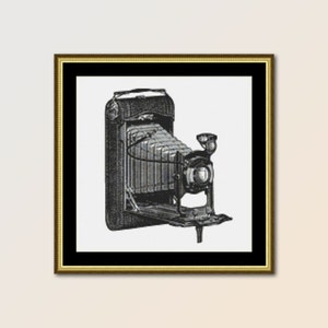 Puede incluir: Una cámara vintage negra y plateada con fuelle y lente. La cámara está en una imagen enmarcada.