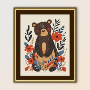 May include: A framed art print featuring a whimsical bear illustration. The bear is brown with a light tan belly and rosy cheeks, surrounded by red flowers and blue foliage. The artwork is set against a cream-colored background.