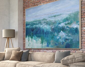 May include: A living room interior with a large abstract painting of blue and green waves hanging above a beige sectional sofa with pillows. The sofa is in front of a brick wall. There is a wooden coffee table with books on it and a brown leather armchair in the foreground.