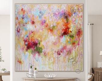 May include: Abstract painting with a colorful, textured, and layered design. The painting features shades of pink, yellow, red, blue, and green. The painting is displayed on a wall above a wooden console table.