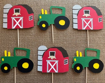May include: Six farm-themed cupcake toppers. Three toppers feature a red barn with a white door and a silo. Three toppers feature a green tractor with yellow wheels.