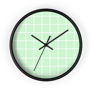 May include: A black framed clock with a light green grid pattern on the face. The clock hands are black.