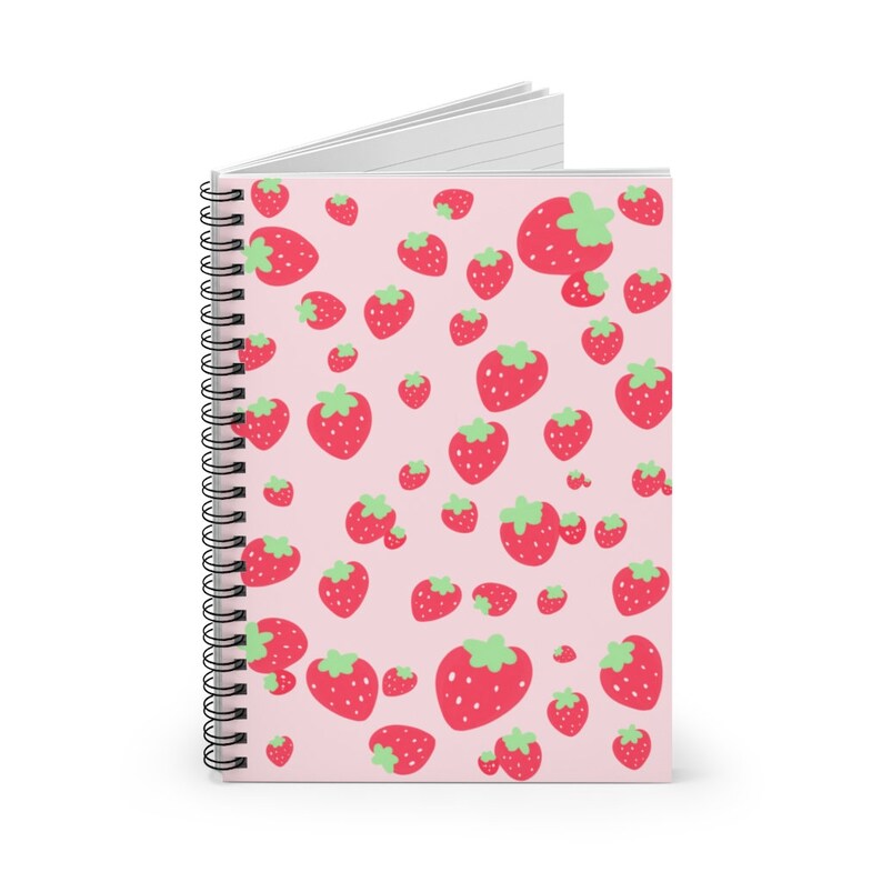 May include: A pink spiral notebook with a repeating pattern of red strawberries on the cover.