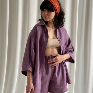 May include: A purple linen shirt and shorts set with a button-up front and a relaxed fit. The shirt has a collar and three-quarter sleeves. The shorts have a drawstring waist and a relaxed fit.