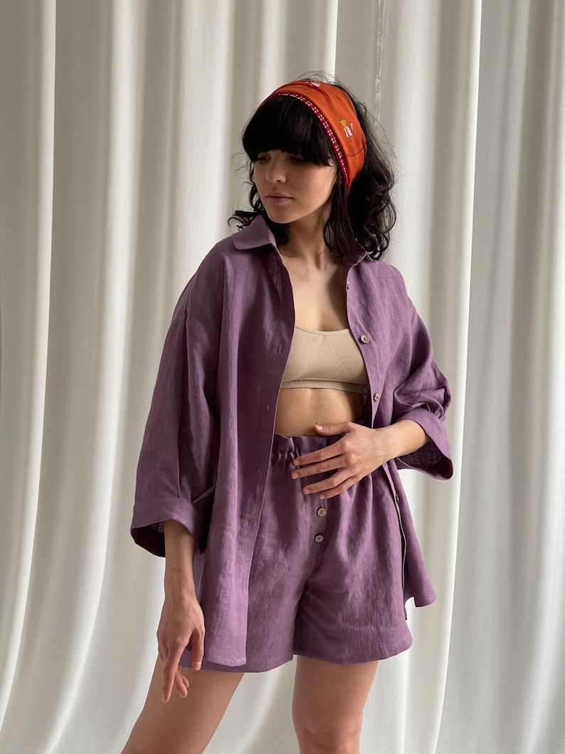 May include: A purple linen shirt and shorts set with a button-up front and a relaxed fit. The shirt has a collar and three-quarter sleeves. The shorts have a drawstring waist and a relaxed fit.