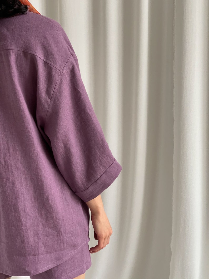 May include: A purple linen shirt and shorts set. The shirt has a relaxed fit and three-quarter sleeves. The shorts are a matching color and have a relaxed fit.