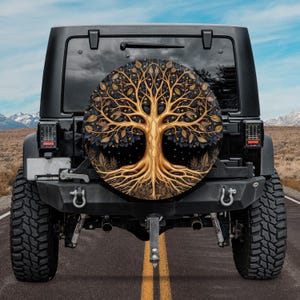 May include: A black Jeep with a spare tire cover featuring a gold tree of life design. The tree has intricate branches and roots, and the background is a dark blue with gold stars.
