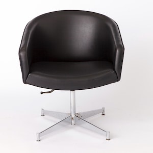 May include: A black leather swivel chair with a chrome base and five legs. The chair has a rounded back and a comfortable seat.