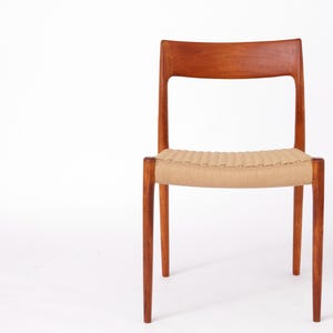 May include: A mid-century modern chair with a woven cane seat and a solid wood frame. The chair is made of a rich reddish-brown wood and has a simple, elegant design.