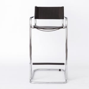 Könnte beinhalten: Ein moderner Barhocker mit einem verchromten Stahlrahmen und einer schwarzen Ledersitzfläche und Rückenlehne. Der Hocker hat ein minimalistisches Design mit einer Fußstütze und einer rechteckigen Rückenlehne. Die Gesamthöhe beträgt ca. 102 cm.