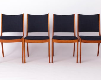 Könnte beinhalten: Ein Set aus vier Esszimmerstühlen mit hellbraunen Holzrahmen und dunkel marineblau gepolsterten Sitzen und Rückenlehnen. Jeder Stuhl hat ein schlichtes Vier-Bein-Design mit einer leicht geschwungenen Rückenlehne für ein einheitliches Bild.