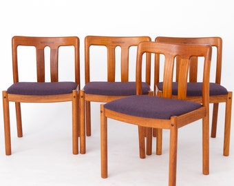 Könnte beinhalten: Vier Holzstühle mit violetten Stoffbezügen. Die Stühle haben ein schlichtes Design mit einer geschwungenen Rückenlehne und vier Beinen.