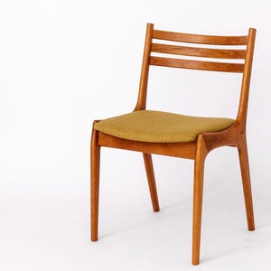 Könnte beinhalten: Ein Holzstuhl mit hellbrauner Oberfläche und einem Sitz aus senfgelbem Stoff. Der Stuhl hat eine Lattenrücklehne und ein schlichtes, modernes Design aus der Mitte des Jahrhunderts.