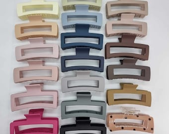 Puede incluir: Un conjunto de 15 pinzas para el pelo en varios colores, incluyendo negro, marrón, rosa, azul y beige. Las pinzas están hechas de plástico y tienen un acabado liso y mate.