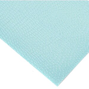 May include: A light blue, textured sheet with a reptile scale pattern. The material has a repeating hexagonal design, creating a textured surface. The sheet is angled, showing the pattern in detail.