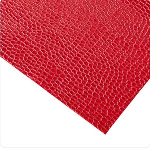 May include: A sheet of red faux leather with a textured, honeycomb-like pattern. The material has a glossy finish and is angled across a white background. The close-up view highlights the detailed texture and vibrant color.