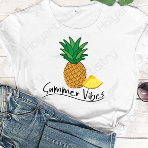 Könnte beinhalten: Weißes T-Shirt mit einem Ananas- und einem Ananasscheiben-Motiv und dem Text "Summer Vibes".