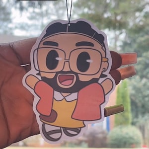 May include: A white car air freshener with a cartoon illustration of a person wearing glasses and a red jacket. The text "Invite i love you" is on the top of the air freshener.