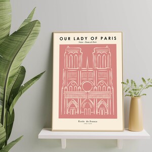 May include: A pink and white minimalist line art print of Notre Dame Cathedral in Paris, France. The print has the text "Our Lady of Paris" and "Notre Dame de Paris" at the top and "Église de France 1163-1345" at the bottom.