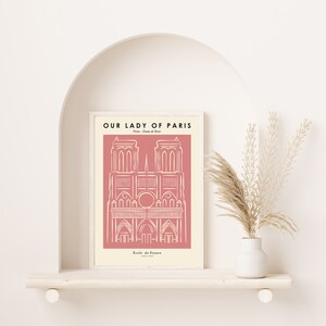 May include: A pink and white printable art print with a line drawing of the Notre Dame Cathedral in Paris, France. The text "Our Lady of Paris" is at the top of the print, and the text "Notre Dame de Paris" is below the drawing. The text "Ecole de France 1163-1345" is at the bottom of the print.