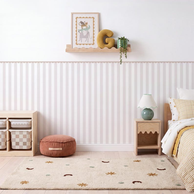 May include: A bedroom featuring light pink and white striped wallpaper, a wooden shelf with a framed animal print, a yellow letter G pillow, and a green plant. Includes a wooden nightstand, a lamp, a terracotta floor cushion, and a patterned rug.