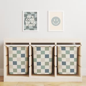 May include: Three white storage bins with lids, each featuring a checkered pattern in shades of green, blue, and beige. The bins are arranged in a row on a wooden shelf.