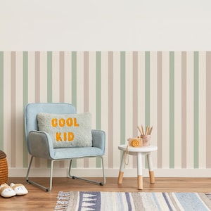 May include: A child's room with a light blue chair, a small white table, and a striped wallpaper in beige, green, and brown. A pillow with the words "COOL KID" is on the chair. A rug and a small toy camera are also visible.