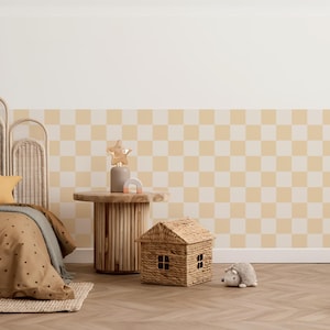 Könnte beinhalten: Ein Kinderzimmer mit einem hölzernen Beistelltisch, einem geflochtenen hausförmigen Korb und einem Stoffigel-Spielzeug. Der Raum hat ein cremefarbenes und gelbes kariertes Wandmuster und ein Bett mit einer gepunkteten Bettdecke.