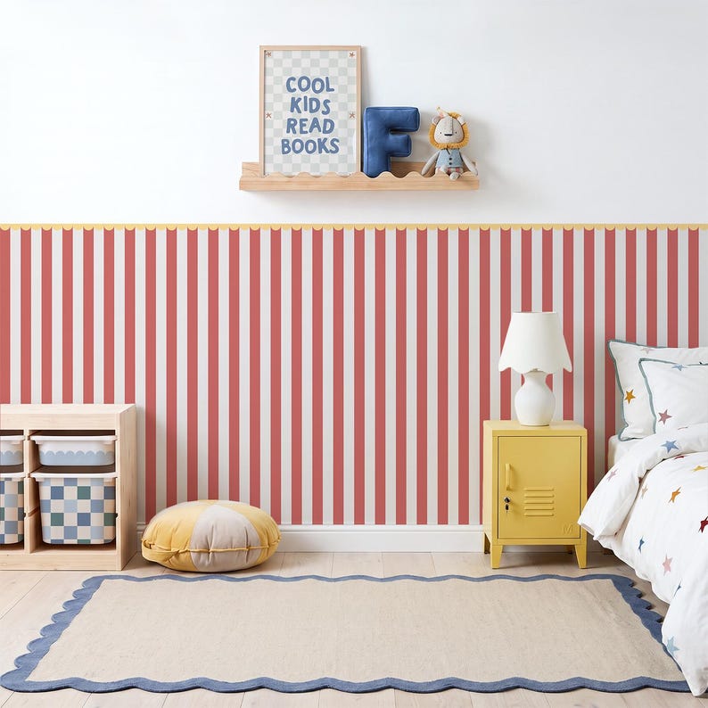 May include: A room featuring red and white vertical striped wallpaper, a light wood storage unit with patterned bins, a yellow metal locker nightstand, a white lamp, a beige rug with a blue scalloped border, and a shelf with a sign reading COOL KIDS READ BOOKS.