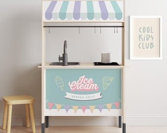 May include: A wooden toy ice cream stand with a blue and white striped awning, a black sink, and a sign that says "Ice Cream Served Daily". There are colorful pennant flags hanging below the sign. A wooden stool is in front of the stand.