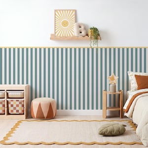 May include: Wallpaper featuring vertical stripes in muted blue and white, accented by a scalloped yellow border. The room includes a wooden shelf with a sun print, a letter B, a plant, a storage unit with patterned bins, and a scalloped rug.
