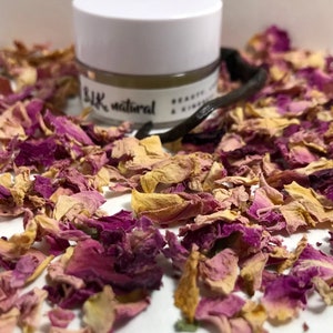 Pu&ograve; includere: Un piccolo barattolo bianco con un coperchio nero e il testo "Silk natural" sull'etichetta. Il barattolo &egrave; circondato da petali di rosa secchi in tonalit&agrave; di rosa e giallo.
