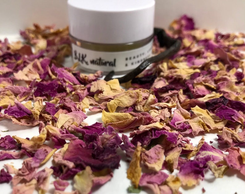 Pu&ograve; includere: Un piccolo barattolo bianco con un coperchio nero e il testo "Silk natural" sull'etichetta. Il barattolo &egrave; circondato da petali di rosa secchi in tonalit&agrave; di rosa e giallo.