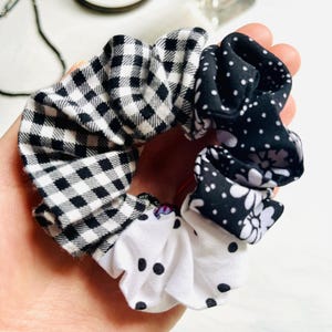 Può includere: Un elastico per capelli a fantasia multipla con motivi a quadri bianchi e neri, pois e floreali. L'elastico per capelli è realizzato in tessuto ed è progettato per tenere i capelli in posizione. Un'aggiunta elegante a qualsiasi acconciatura.