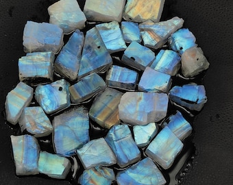 May include: A collection of iridescent blue and white labradorite gemstone chips. The chips are various sizes and shapes, and have a shimmering, rainbow-like effect.