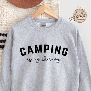 May include: Gray sweatshirt with the text "CAMPING is my therapy" in black.