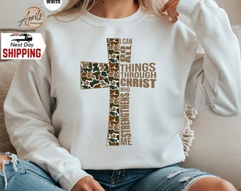 May include: White sweatshirt with a camouflage cross and the text "I can do all things through Christ who strengthens me".