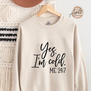 May include: A beige sweatshirt with the text "Yes, I'm cold. ME 24-7" printed in black.