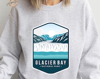 Peut inclure: Sweat-shirt gris avec un motif bleu et blanc du parc national de Glacier Bay. Le motif représente une chaîne de montagnes, un glacier et une étendue d'eau.