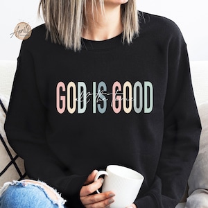 May include: A black sweatshirt with the text "GOD IS GOOD" in rainbow colors. The text is in a modern font style.