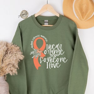 May include: A green sweatshirt with an orange ribbon and the text "I wear orange for someone I love".