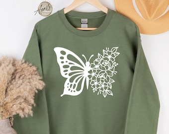 May include: A green sweatshirt with a white butterfly and floral design. The butterfly is half-covered in flowers.