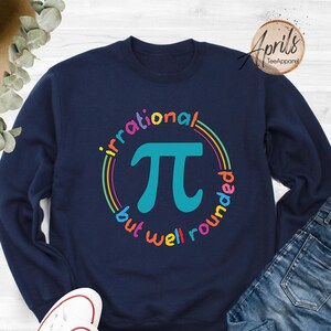 May include: A navy blue sweatshirt with a colorful graphic of the mathematical symbol pi. The graphic says "irrational but well rounded".