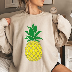 May include: A beige sweatshirt with a green and yellow pineapple graphic.