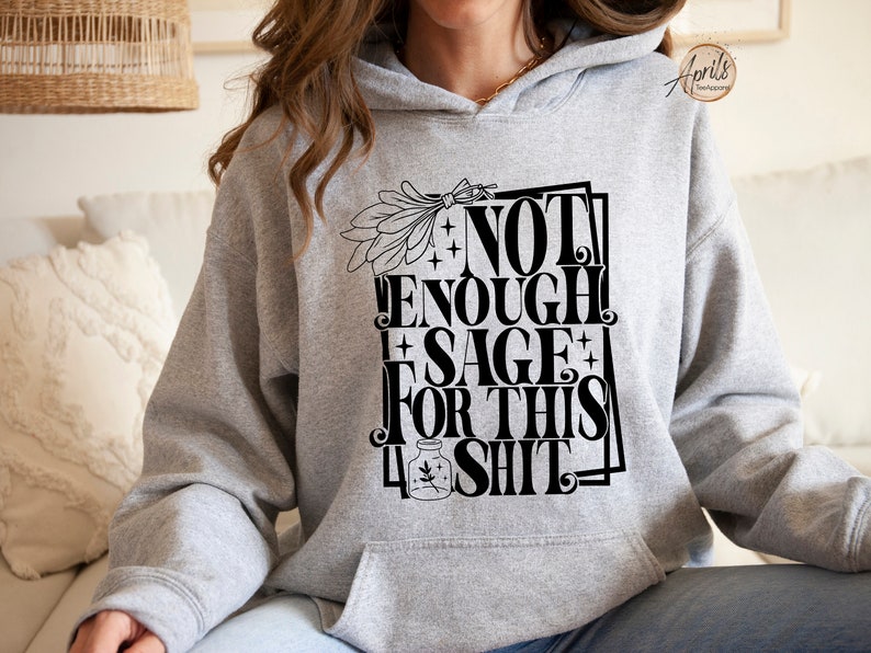 Puede incluir: Sudadera con capucha gris con un estampado gr&aacute;fico negro que dice "No hay suficiente salvia para esta mierda".