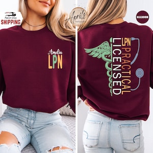 May include: Maroon sweatshirt with "Amelia LPN" printed on the front. The back features "LPN PRACTICAL LICENSED" with a medical caduceus and stethoscope design. The sweatshirt is a comfortable, casual style.