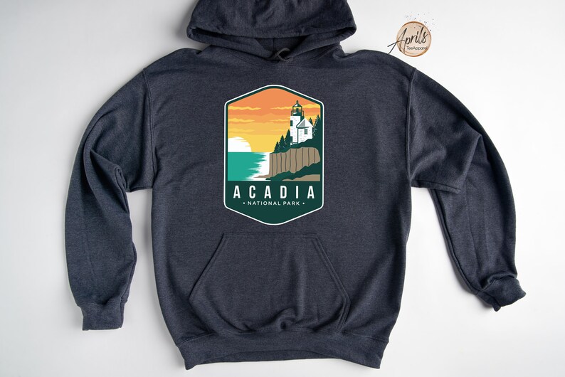 K&ouml;nnte beinhalten: Ein dunkelblauer Kapuzenpullover mit einem grafischen Design eines Leuchtturms und dem Text "Acadia National Park".