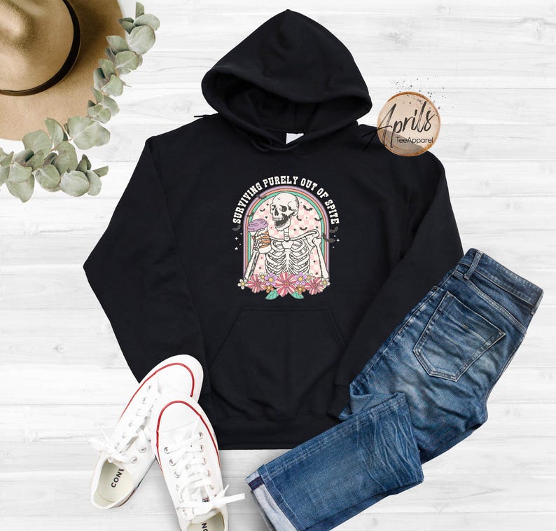 May include: Black hoodie featuring a graphic of a skeleton holding a drink with the text "Surviving purely out of spite".